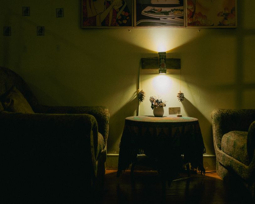 A warmly lit living room showcasing armchairs, a table, and soft lighting for a cozy ambiance.